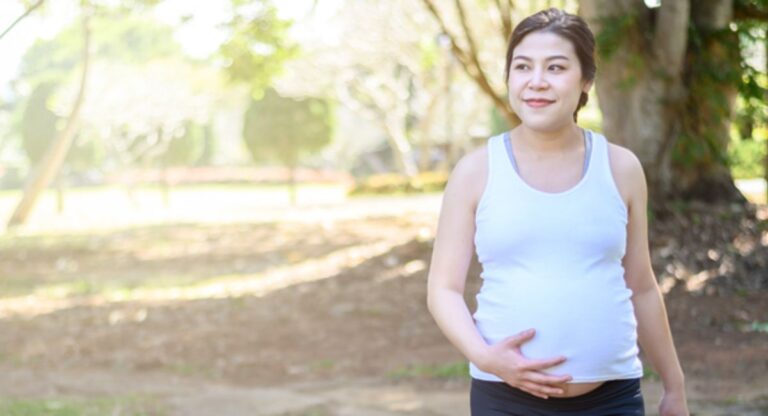 Pregnant woman checking her weight on a scale and wondering if losing weight during pregnancy is normal and safe for her baby.